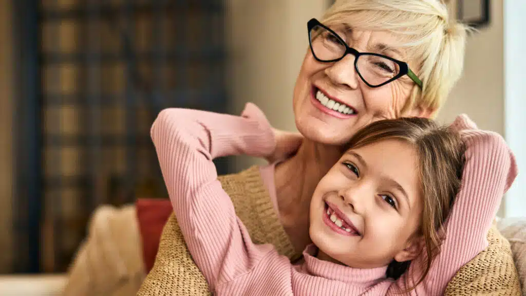 A grandmother who had dental implant surgery sitting with her granddaughter