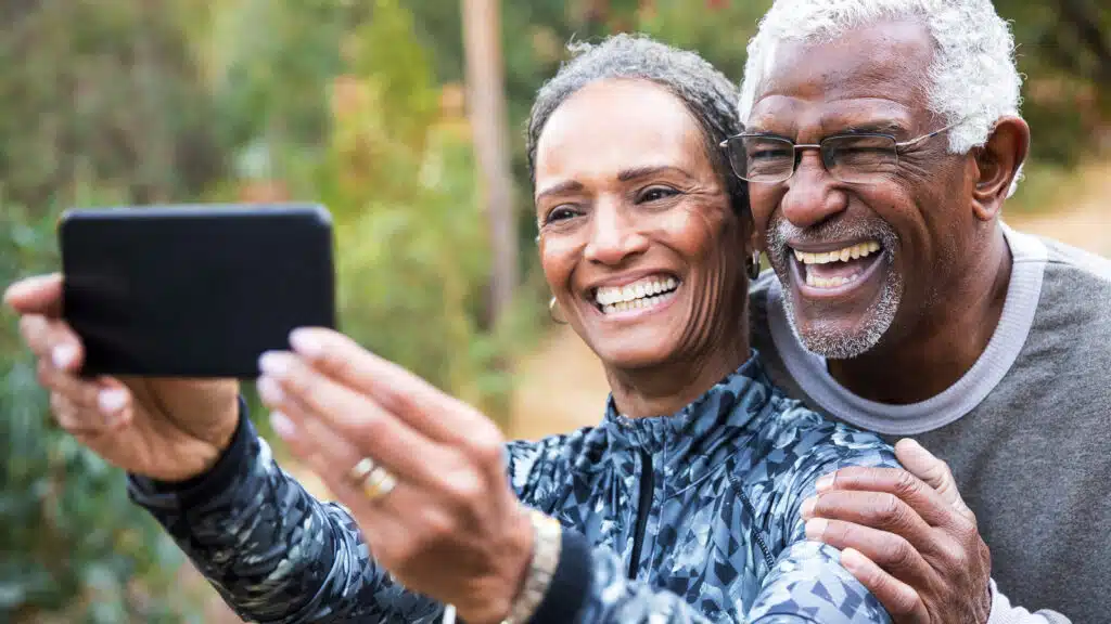 An older couple with big smiles taking a selfie photo