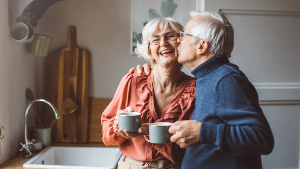 An older man who benefitted from a periodontics procedure in Colorado Springs kissing his wife